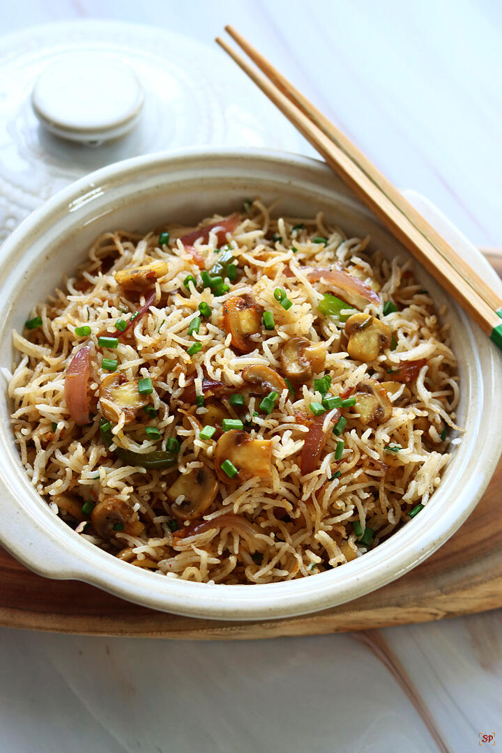 mushroom fried rice served in a bowl with chopsticks on the side