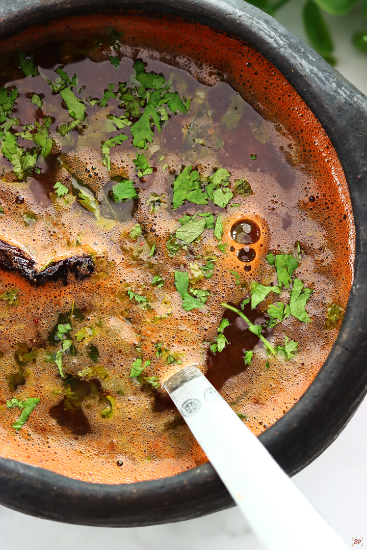 tomato rasam served in a black clay pot