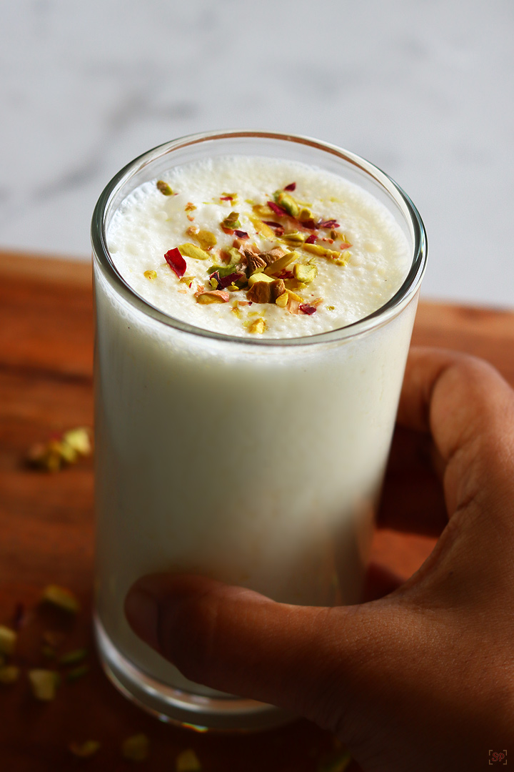 sweet lassi served in a tall glass with nuts