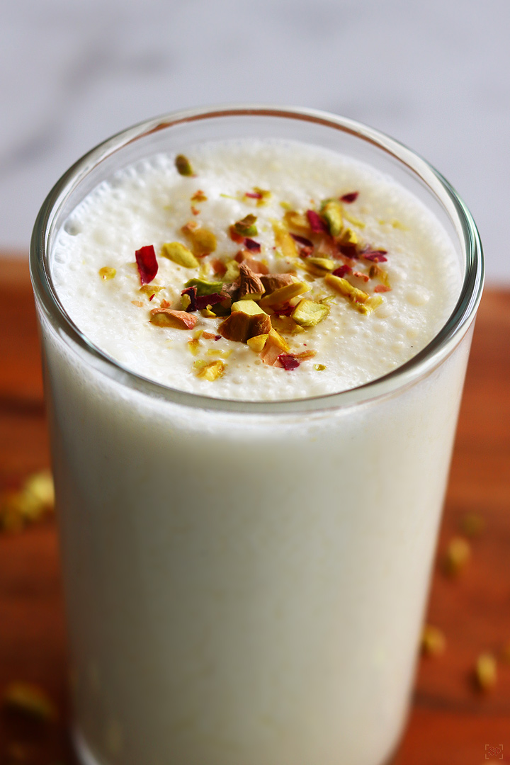 sweet lassi served in a tall glass with nuts