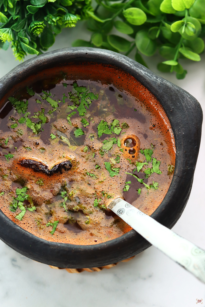 tomato rasam served in a black clay pot