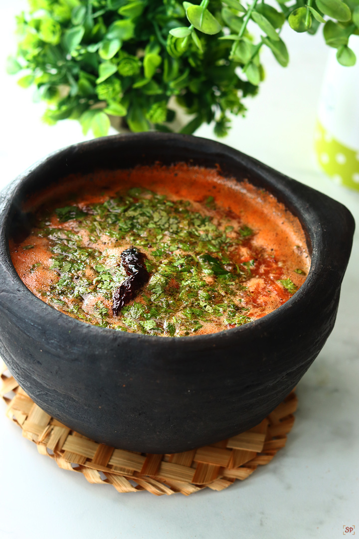 tomato rasam served in a black clay pot