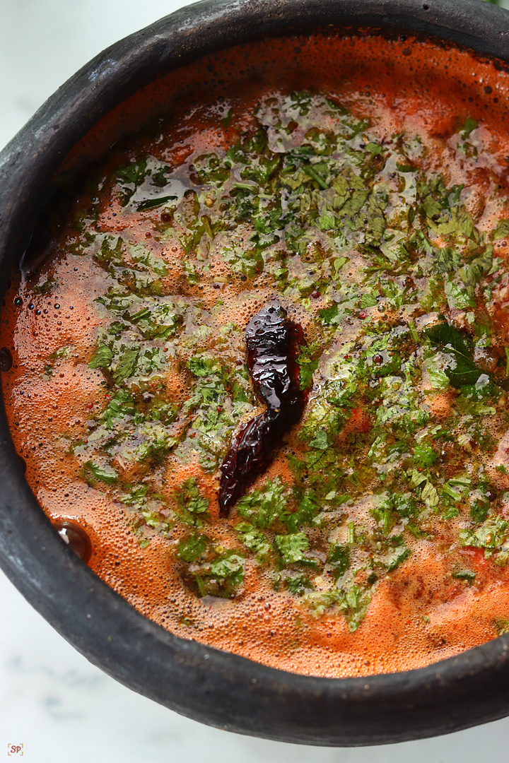 tomato rasam served in a black clay pot